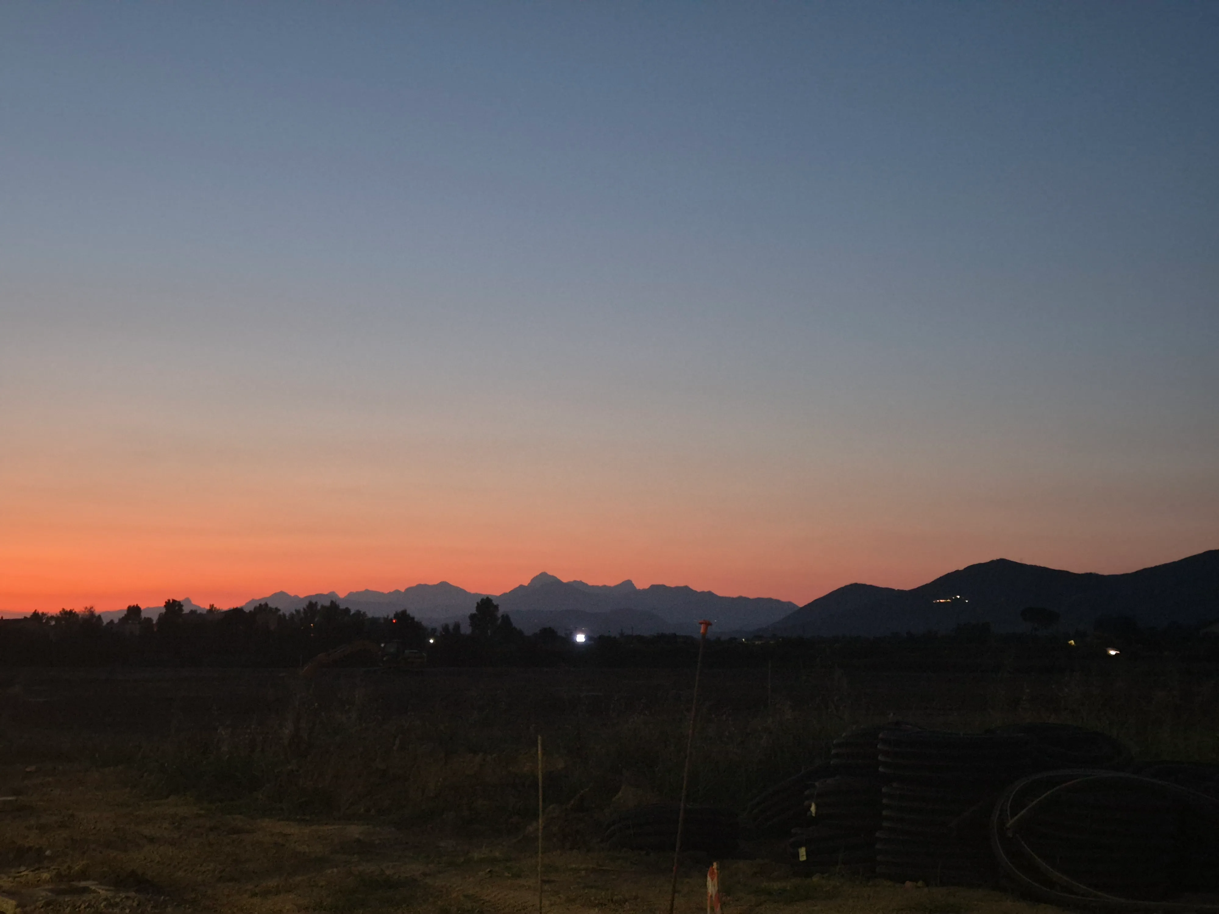 An orange horizon fading into blue above distant mountains